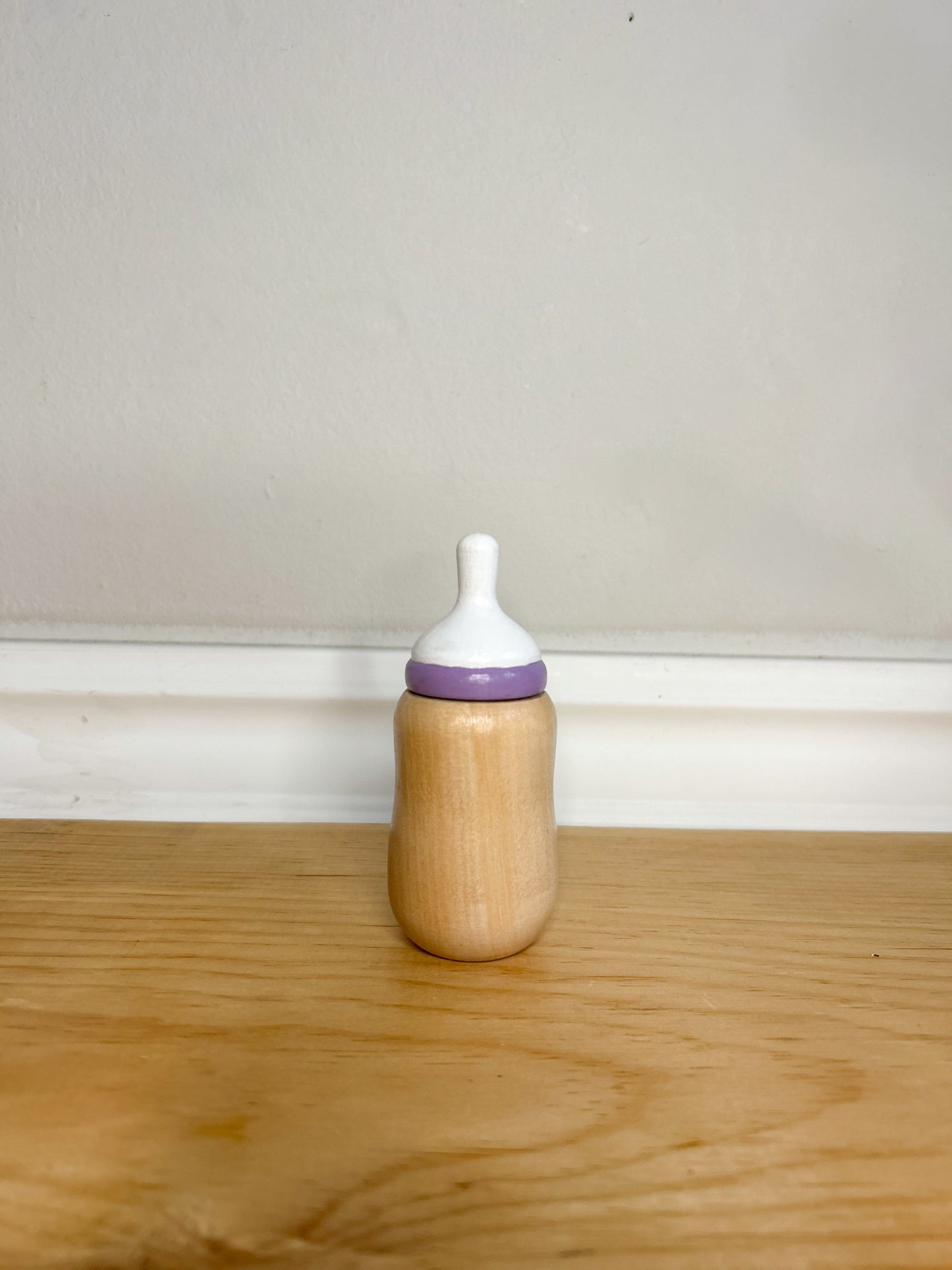 wooden baby doll bottle with purple and white top